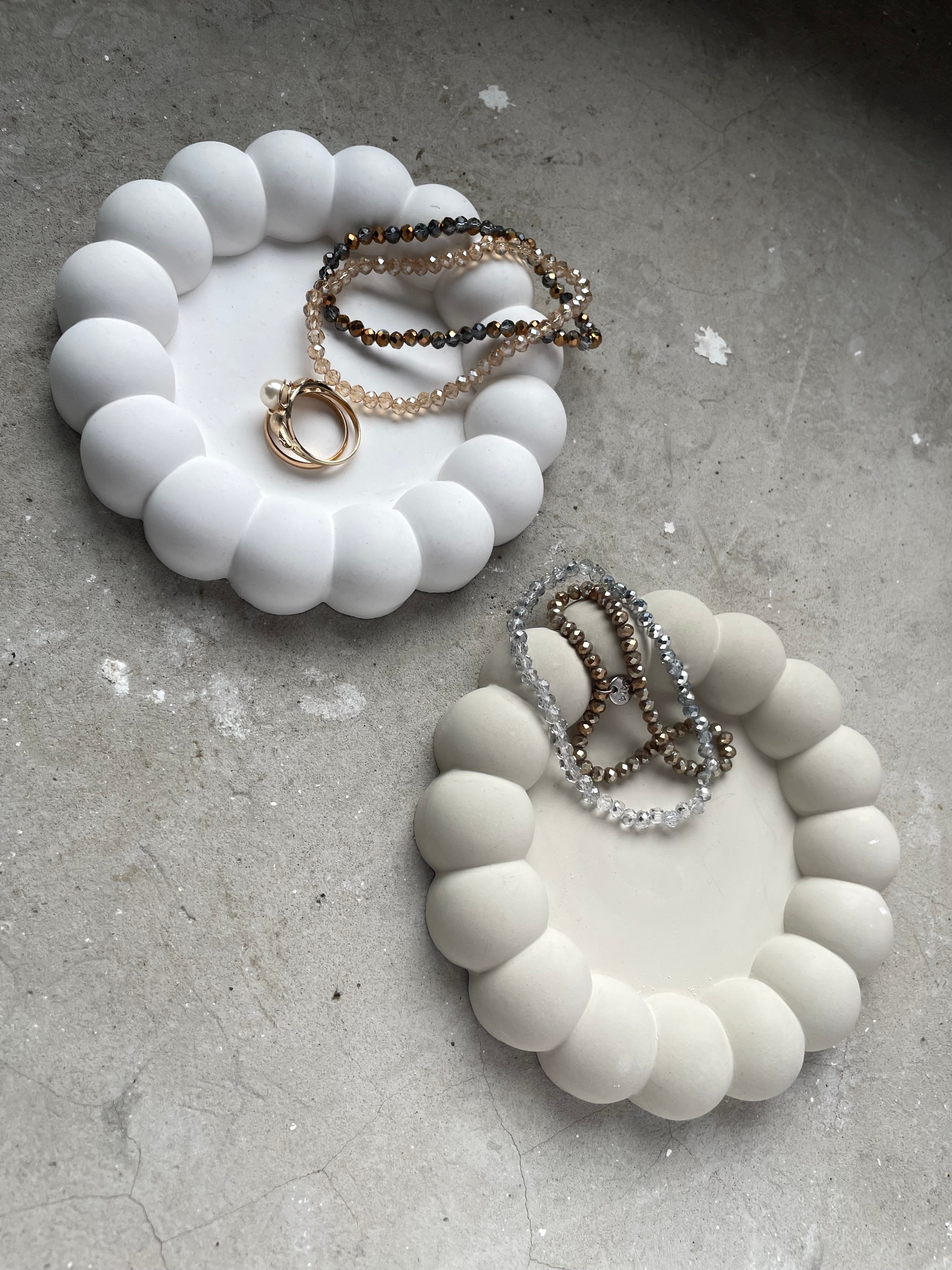 Keramikschale mit charakteristischem Bubble-Rand, in Handarbeit gegossen und geschliffen. Ideal als kleine Ablage im Badezimmer, Schlafzimmer oder auf dem Schreibtisch. Die kugeligen Rundungen sorgen für eine moderne, trendige Optik, inspiriert von aktuellen Pinterest- und Instagram-Interiortrends. Langlebig, pflegeleicht und dekorativ. Perfekt für Schmuck, Haarnadeln oder Mini-Accessoires. Ein charmantes, modernes Deko-Piece für jeden Raum.
süß als Weihnachtsgeschenk, Mitbringsel für Freundin, Raysin 