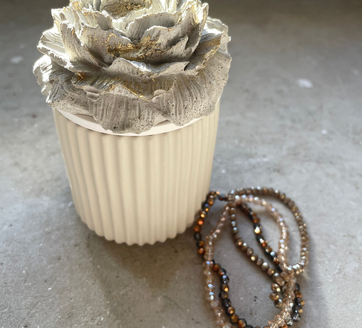 Keramikdose mit gegossener Betonblüte als Deckel, perfekt für Schmuck, Ringe, kleine Kostbarkeiten oder besondere Geschenke. Warme Naturfarbtöne und goldene Akzente verleihen dem Stück eine elegante, moderne Optik. Handgefertigt, stabil und langlebig. Ideal für Schlafzimmer, Badezimmer oder als dekoratives Element im Wohnzimmer. Ein schönes Geschenk für Frauen, die Blumen und Minimal Design lieben.