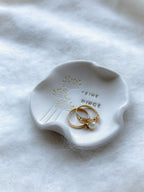 Kleine, hochwertige Keramikschale mit organischer Form, dekorativer Wildblumenstruktur und edler Goldverzierung, handgemacht mit der Aufschrift „Feine Dinge“.


