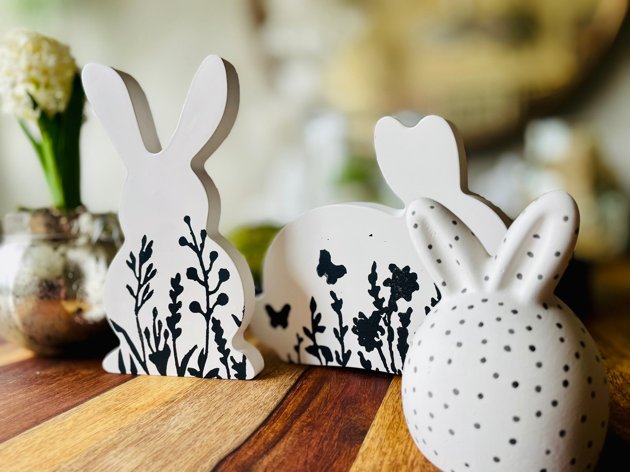 Ästhetischer Blickfang für die Ostertafel ein handgemachter weißer Keramikhase dessen Rücken mit einem dichten Teppich aus geprägten Frühlingsblüten verziert ist.