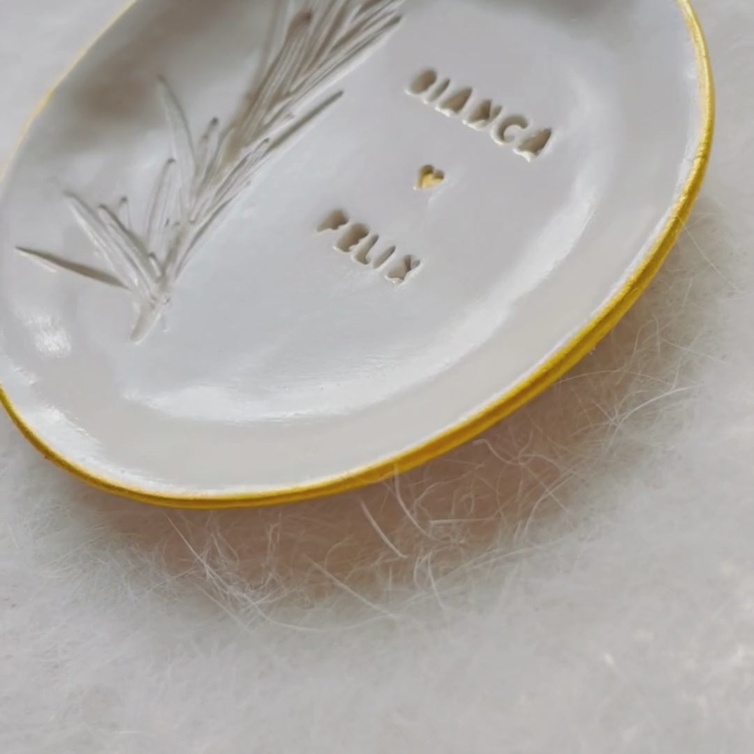 Custom ceramic ring holder for wedding ceremonies, glossy glaze, with names and real rosemary embossing.

