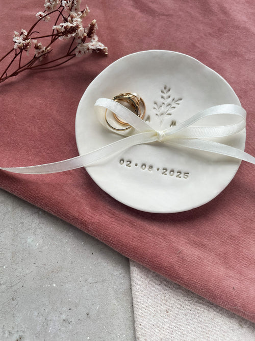 Zwei Eheringe liegen in einer personalisierten Boho-Ringschale mit feiner Zweigprägung – ein handgefertigtes Hochzeitsaccessoire aus Keramik, das als stilvolle Ringkissen-Alternative überzeugt.


