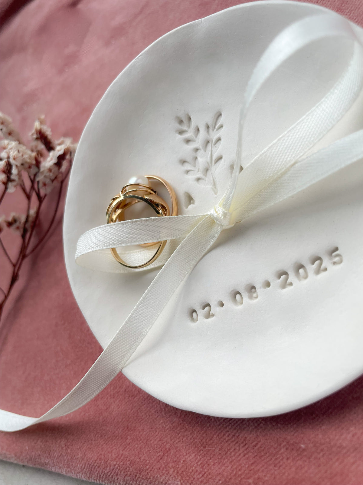 Boho-inspirierte Keramik-Ringschale mit handgeprägtem Zweig, Initialen und Datum – dekorativ inszeniert mit Trockenblumen und Naturmaterialien, perfekt für natürliche Hochzeiten im Grünen oder liebevolle freie Trauungen.

